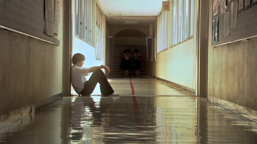 A quiet school hallway scene in All About Lily Chou-Chou (2001) captures the loneliness of youth.