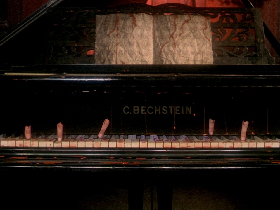 A grand piano with disembodied fingers on its keys in House (1977).