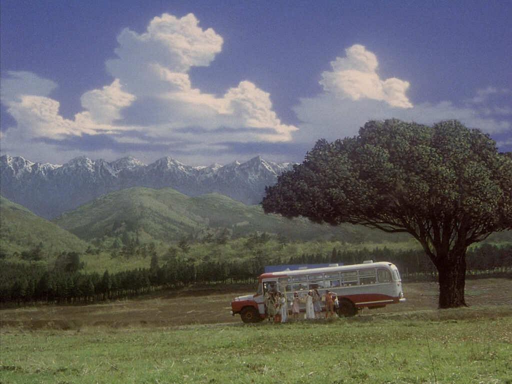 A bus stops beneath a large tree in the countryside in House (1977).