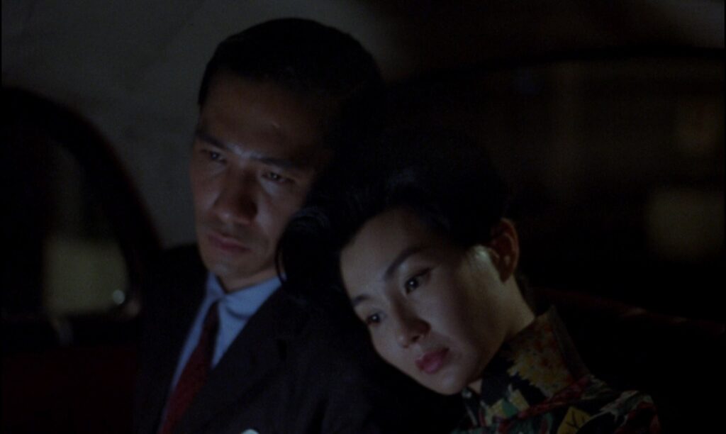 Tony Leung and Maggie Cheung share a quiet moment in a taxi in In the Mood for Love (2000), reflecting unspoken affection and longing.