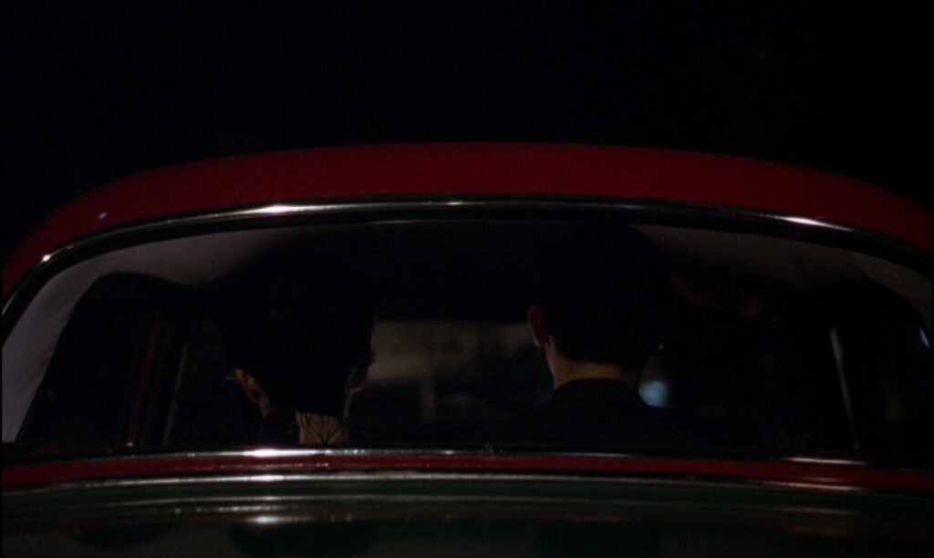 A nighttime taxi scene in In the Mood for Love (2000) captures the film's quiet intimacy and emotional distance.