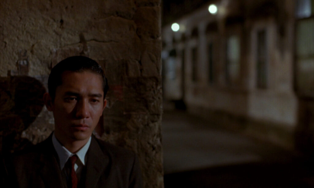 Tony Leung stands alone at night in In the Mood for Love (2000), captured with Wong Kar-wai's signature mood.
