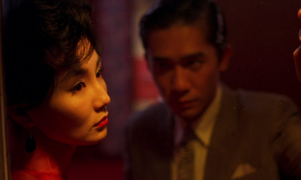 Maggie Cheung and Tony Leung share a quiet moment in In the Mood for Love (2000), framed with warm lighting.
