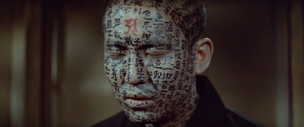A close-up of a man's face covered with Japanese calligraphy in Kwaidan (1964).