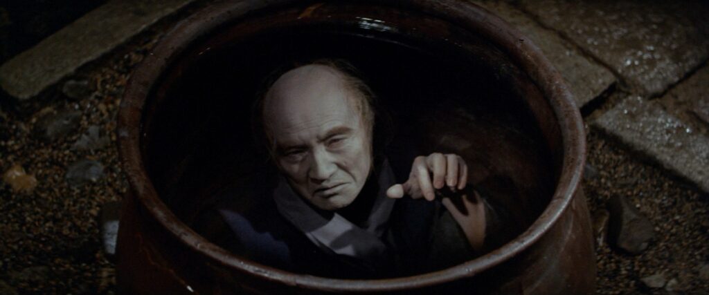 An elderly man reaches out from inside a large ceramic jar in Kwaidan (1964).