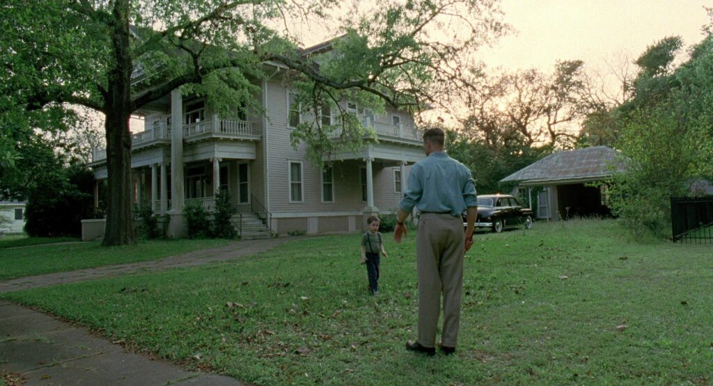 A father and son stand together outside their home in The Tree of Life (2011).