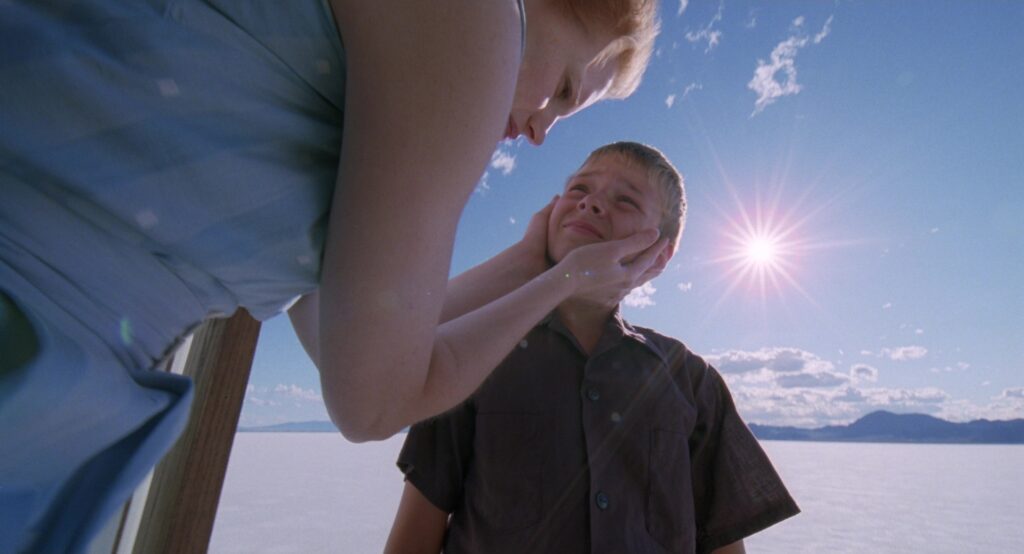 Jessica Chastain gently holds a young boy's face beneath a bright sky in The Tree of Life (2011).