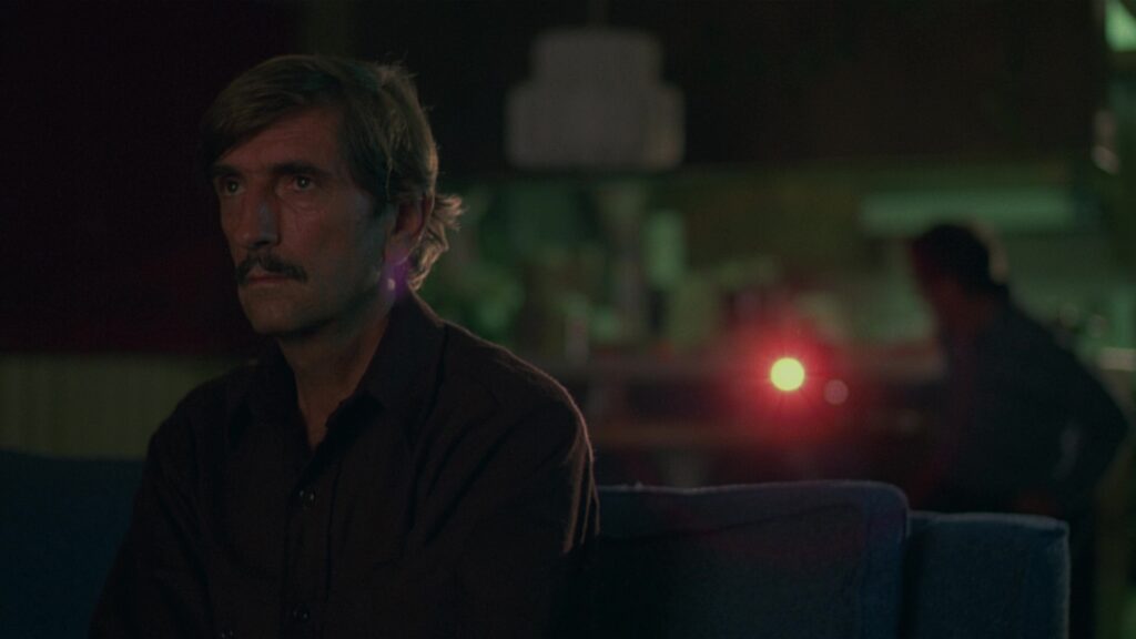 A contemplative Travis Henderson in Paris, Texas (1984), captured in soft neon lighting.