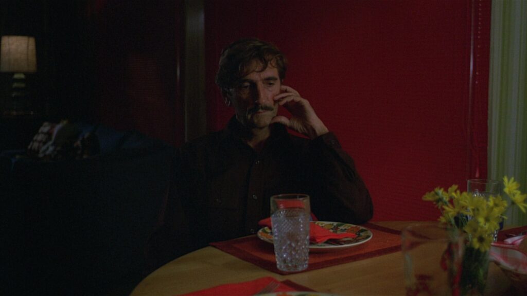 Travis Henderson sits alone in a dimly lit diner in Paris, Texas (1984), lost in thought.