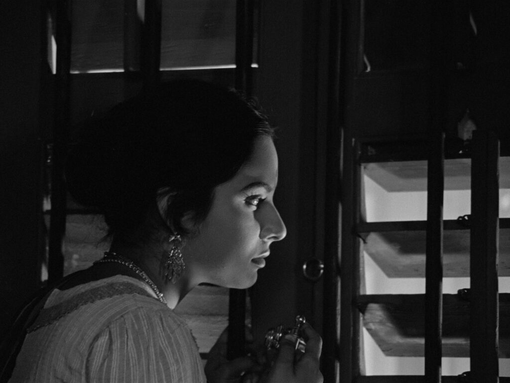 Charulata lost in thought by the window, one of many quiet, wordless moments in Charulata (1964)