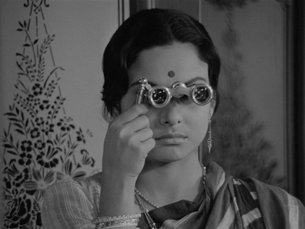 Charulata watches the street below through her opera binoculars, one of the most iconic images in Charulata (1964)