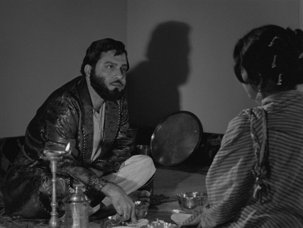 Bhupati and Charulata share a quiet meal together, lit by an oil lamp, in Charulata (1964)