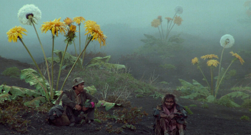 A man speaks with an elderly survivor among oversized flowers in Dreams (1990).