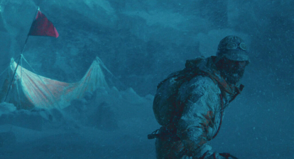 A mountaineer struggles through a blizzard beside a snow-covered tent in Dreams (1990).
