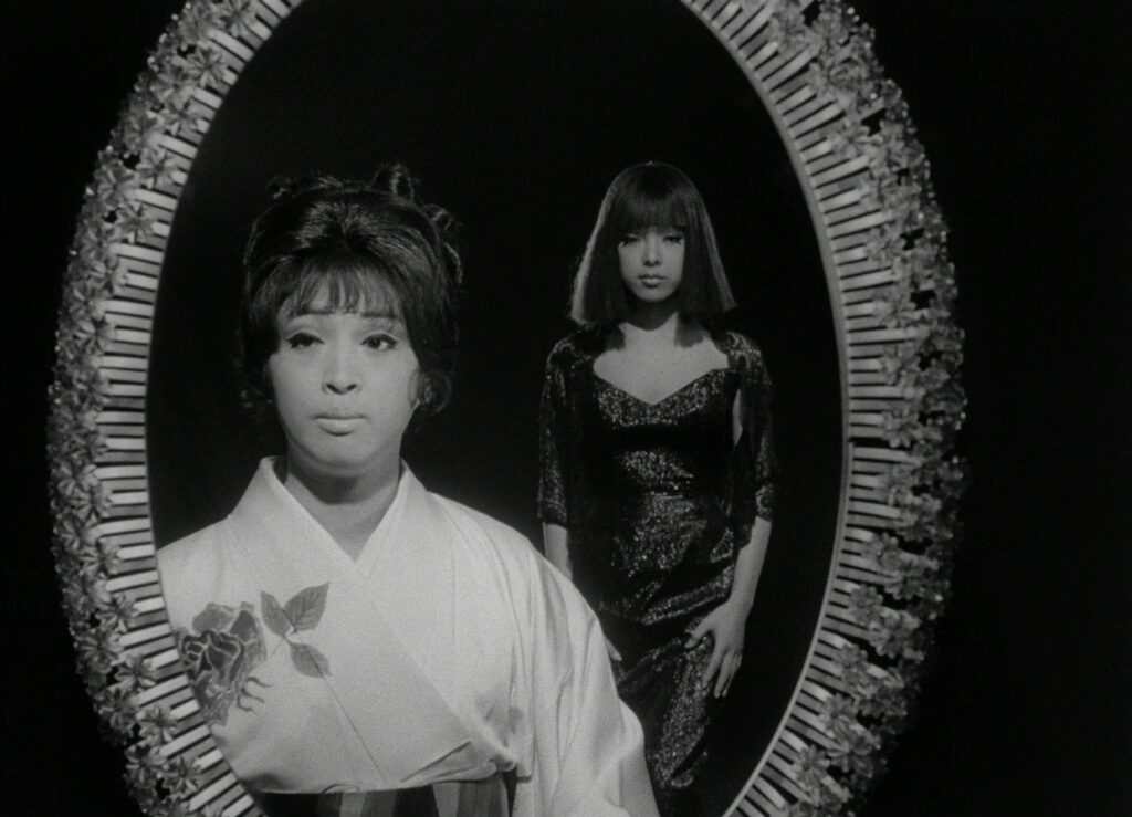 Two women stand before an ornate oval mirror in Funeral Parade of Roses (1969).