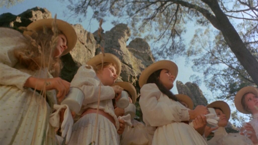 Schoolgirls pause at the base of Hanging Rock during the picnic scene in Picnic at Hanging Rock (1975)