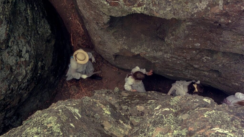 Schoolgirls climbing into a rock crevice at Hanging Rock in Picnic at Hanging Rock (1975)