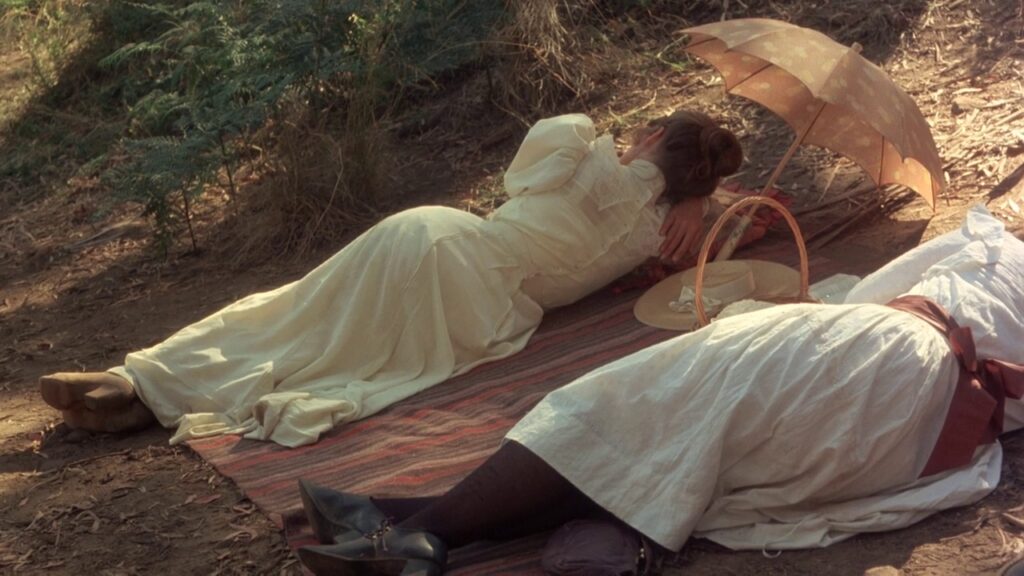Girls resting on a picnic blanket beside a parasol in Picnic at Hanging Rock (1975)