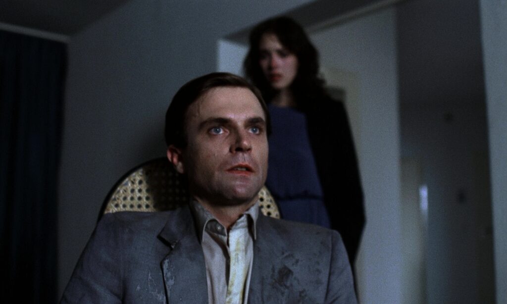 Sam Neill looking shaken as Isabelle Adjani stands behind him in Possession 1981