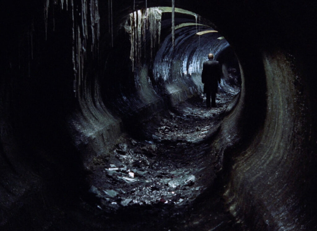 A figure walks through a dark, dripping tunnel in the Zone, Stalker (1979) cinematography