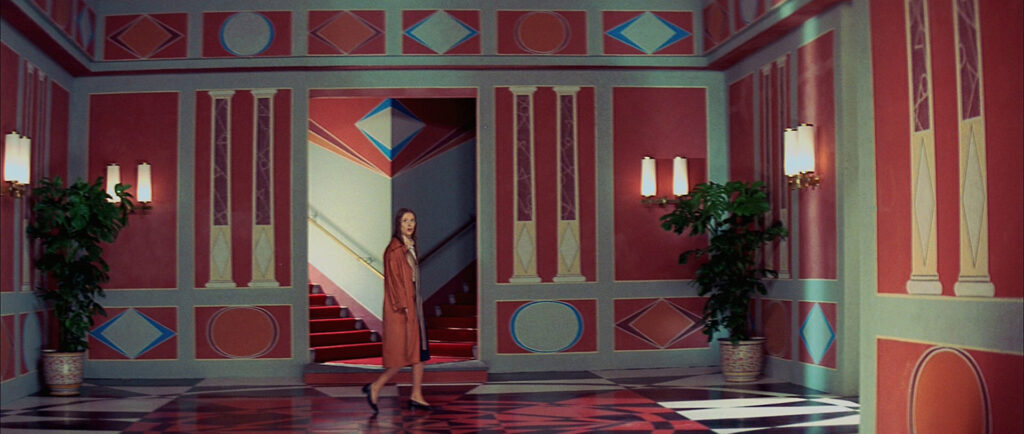 A young woman walks through the colorful halls of the dance academy in Suspiria (1977).