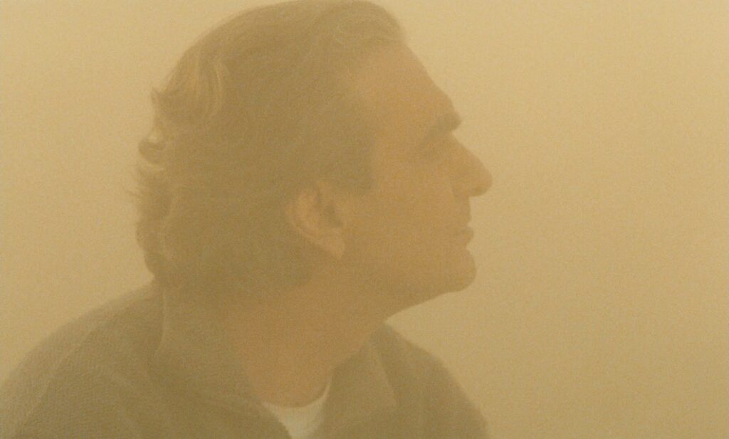 Taste of Cherry (1997): A Film About Wanting to Die That Makes You Want to Live Taste of Cherry 1997 Review 3 Close-up profile shot of Mr. Badii shrouded in dust, Taste of Cherry 1997
