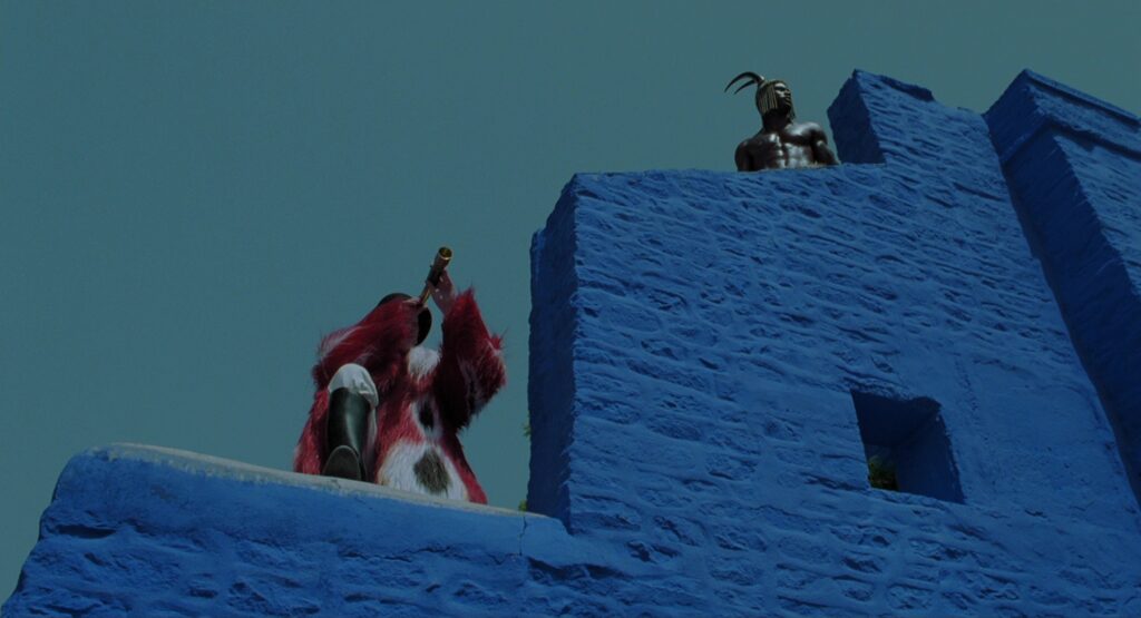 The Fall (2006) — two costumed figures atop a vivid blue fortress wall, showcasing the film's striking production design