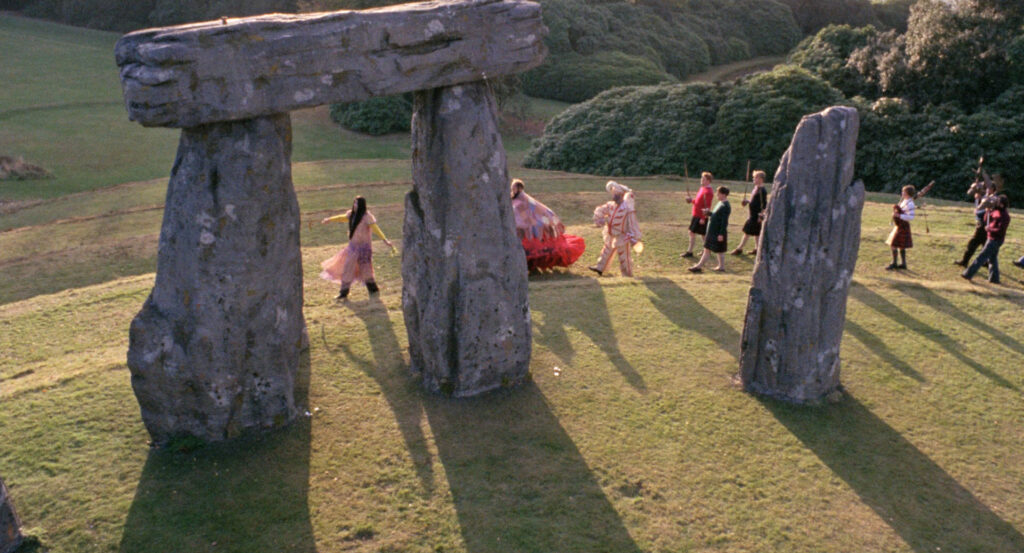 A colorful procession passes through ancient standing stones in The Wicker Man (1973).