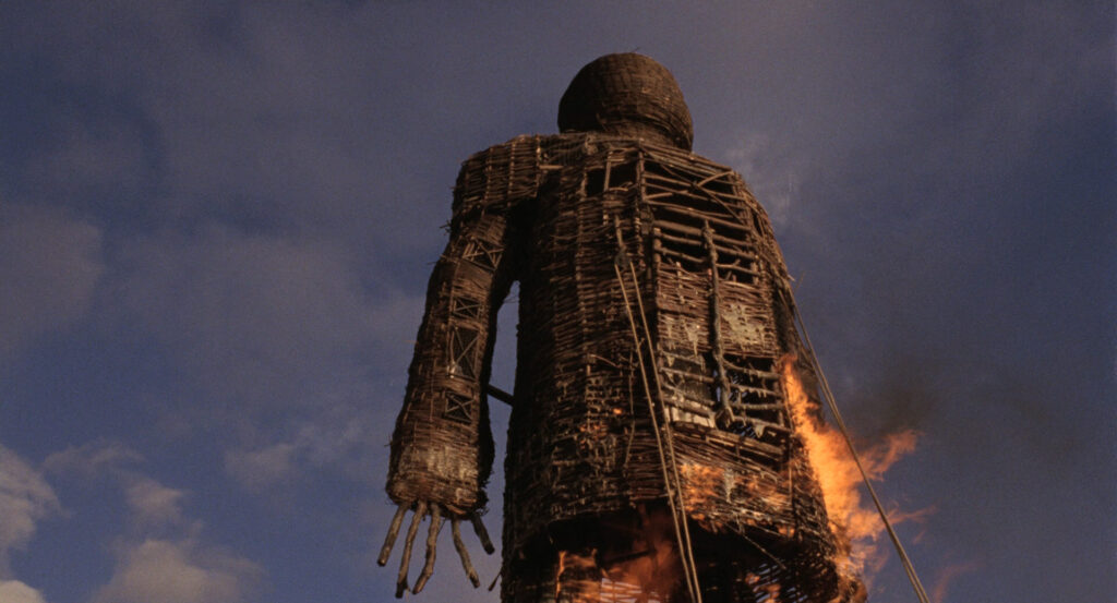 The giant wicker figure begins to burn against a darkening sky in The Wicker Man (1973).