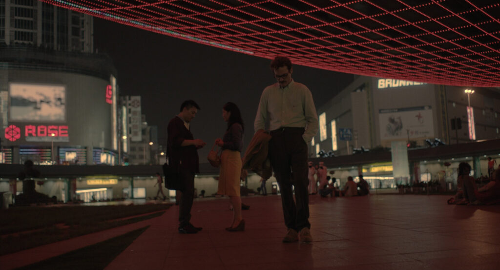 Theodore standing in a neon-lit city plaza at night in Her (2013)