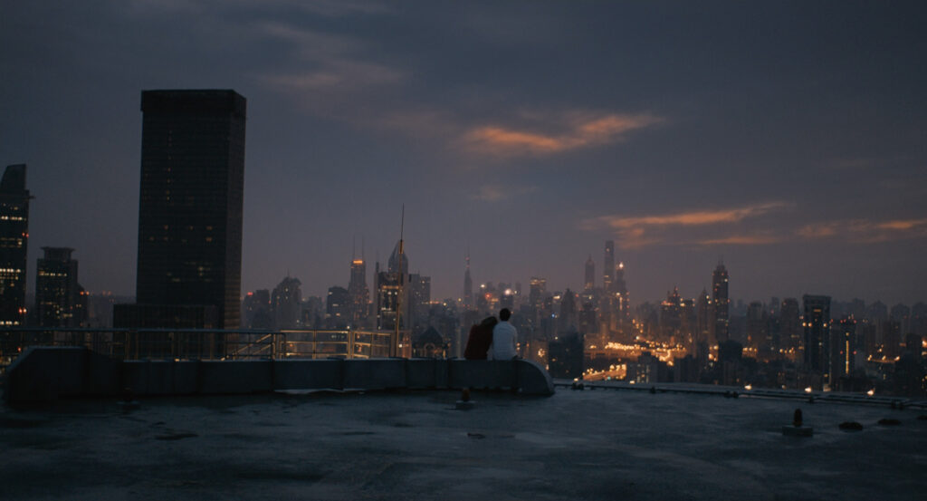 Two silhouettes sitting on a rooftop overlooking the city skyline in Her (2013)