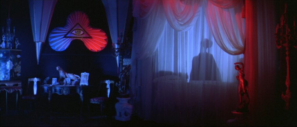 A mysterious shadow appears behind sheer curtains inside a dimly lit room in Suspiria (1977).